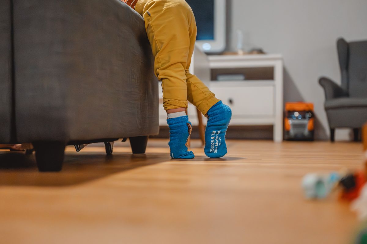 Kleine Beine schauen unter dem Sofa hervor